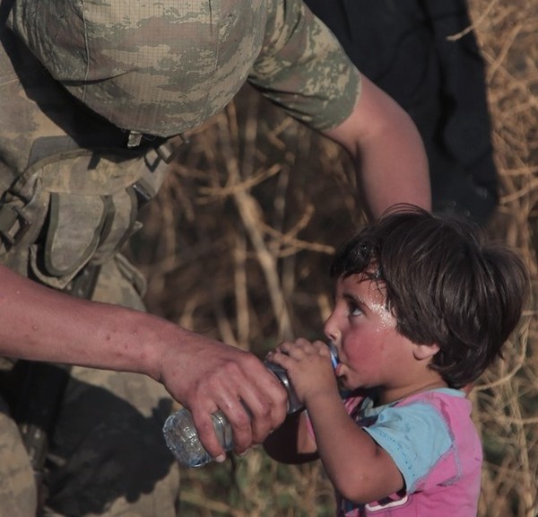 Một người lính Thổ Nhĩ Kỳ chia sẻ nước uống với một trẻ Syria phải hứng chịu cuộc chiến vô nghĩa tại nước này đang trên đường tị nạn. Ảnh: AP